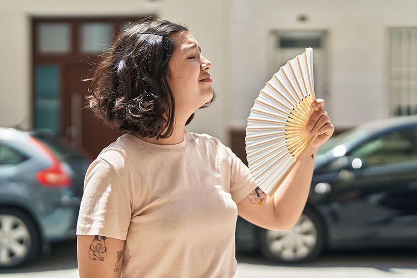 Young woman using handfan at street